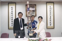 2002年4月18日體育系同學為感謝張鏡湖董事長、林彩梅校長對體育活動的支持，將高達一公尺的總錦標獎座獻給張董事長與林校長的圖片