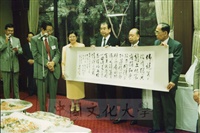 1995年7月8日日本創價大學舉辦酒會歡迎董事長張鏡湖、校長林彩梅等訪問團 ，張董事長在會場上致贈書畫予創大的圖片