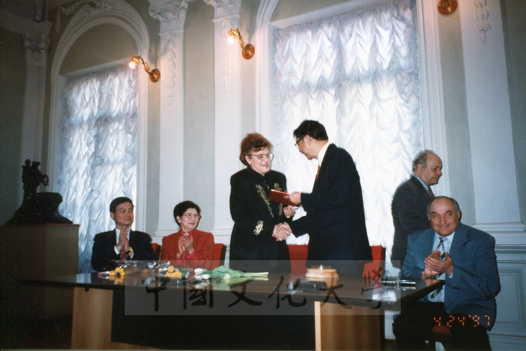 1997年4月23日及24日董事長張鏡湖帶領校長林彩梅、學務長高輝、俄研所所長明驥及國際學術合作組組長孫德宜拜會俄羅斯聖彼得堡大學，張董事長並榮獲該校名譽博士學位，由該校校長薇爾碧芝卡雅女士親自頒贈的圖檔，第7張，共32張