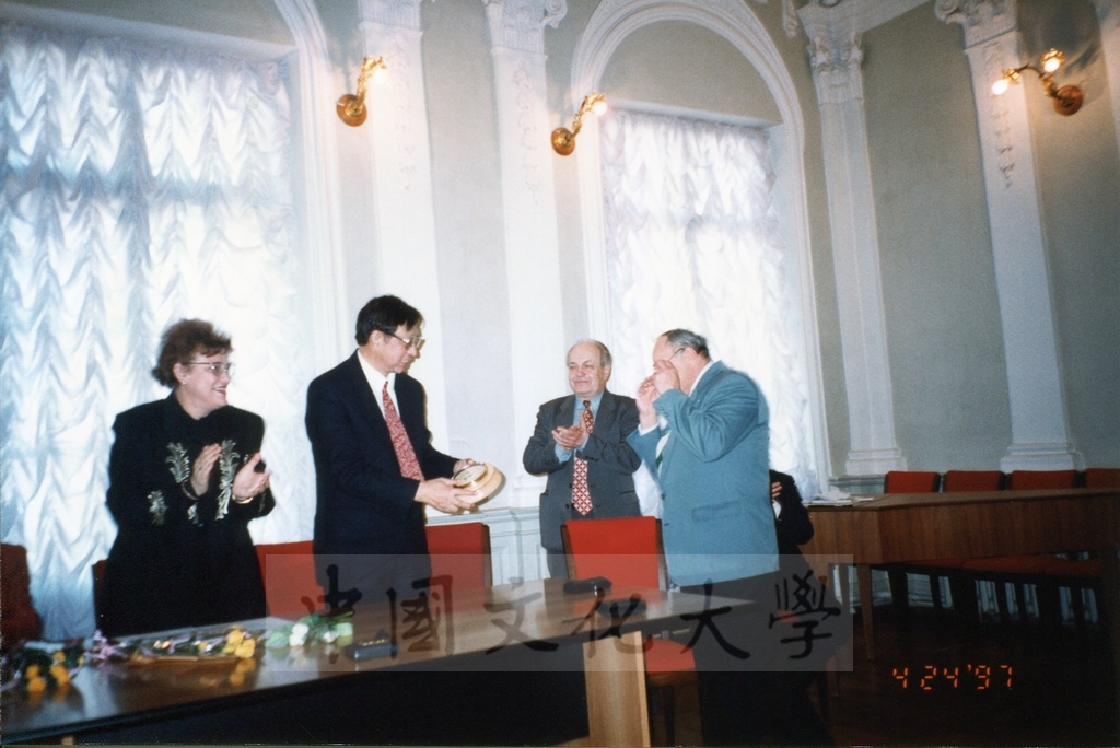1997年4月23日及24日董事長張鏡湖帶領校長林彩梅、學務長高輝、俄研所所長明驥及國際學術合作組組長孫德宜拜會俄羅斯聖彼得堡大學，張董事長並榮獲該校名譽博士學位，由該校校長薇爾碧芝卡雅女士親自頒贈的圖檔，第8張，共32張